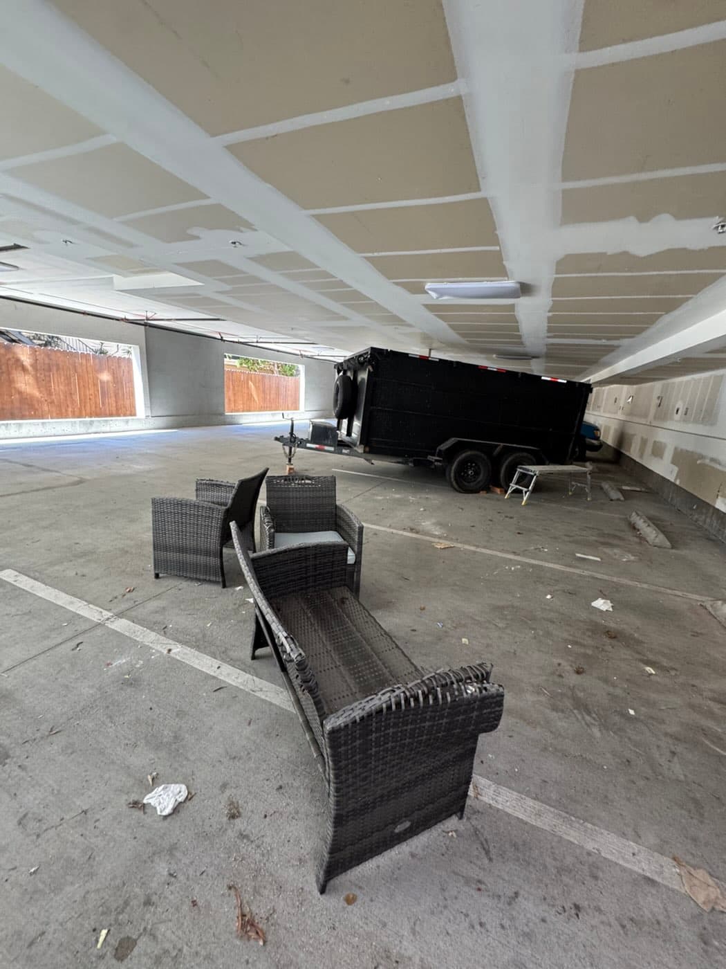 Gray wicker patio loveseat and two chairs set out for pickup in a North Park garage