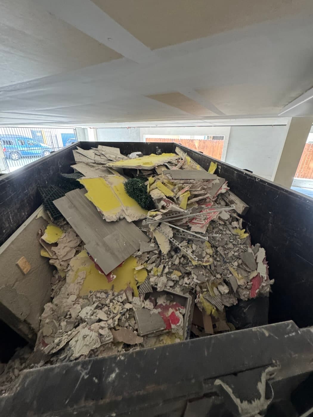 Dump trailer full of drywall, tile and vinyl plank renovation debris in a North Park parking garage